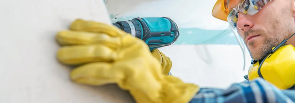 Tradesman drilling into a wall on added work that needs a signed authorization