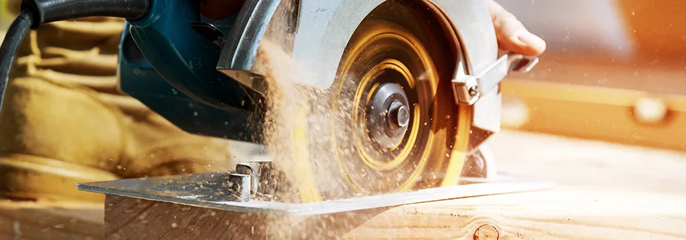 A carpenter cuts lumber with a circular saw; construction costs happen job by job in the field, which generic accounting software was never built to track