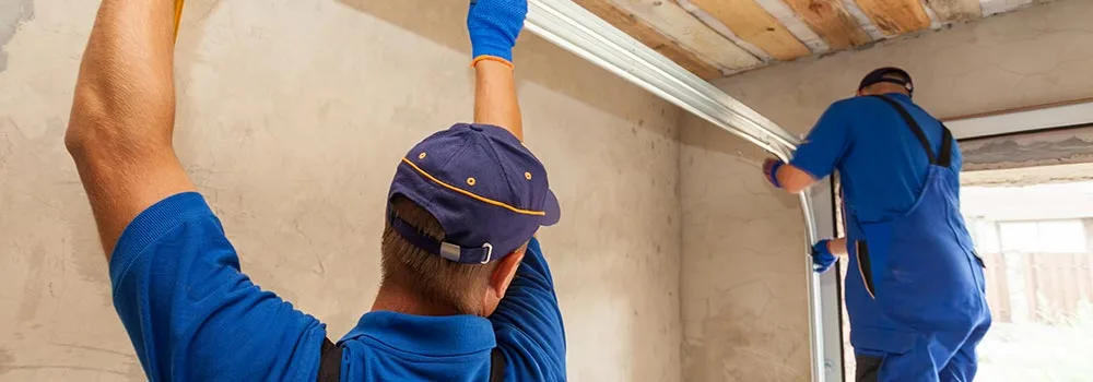 Two garage door installers fit a track together; specialty subcontractors need the site ready the day they arrive
