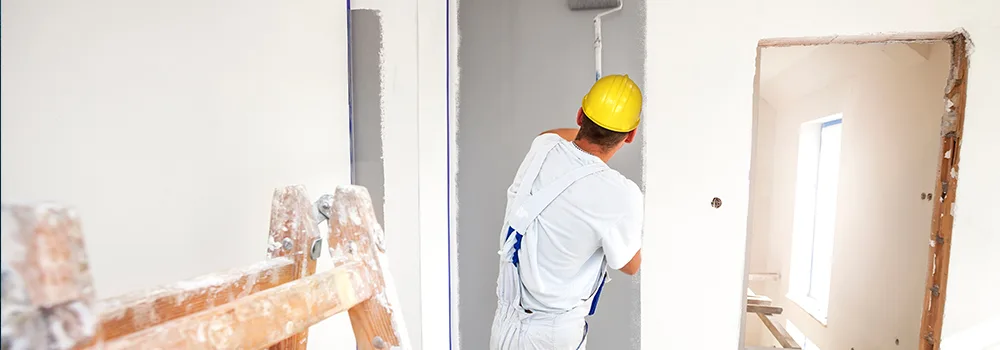 A painter works with a roller beside a ladder and bucket; in progress shots like this make easy, honest social media content
