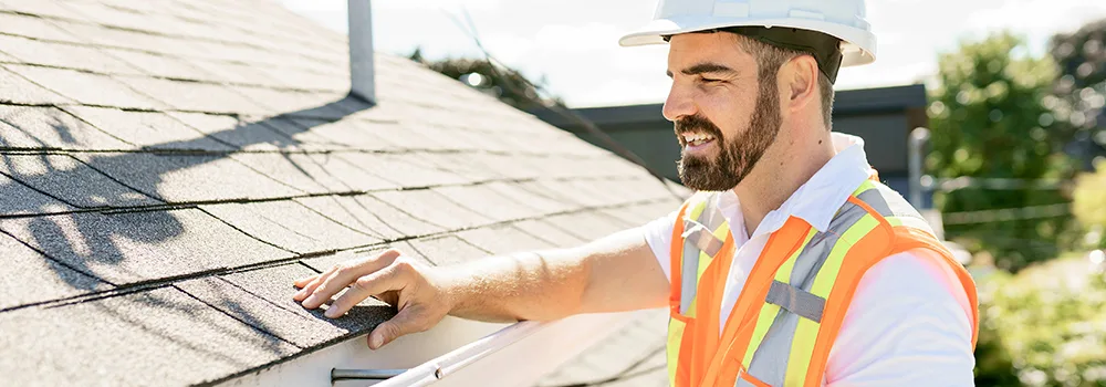 Roofer checking shingle courses up close, the kind of detail a thorough estimate captures
